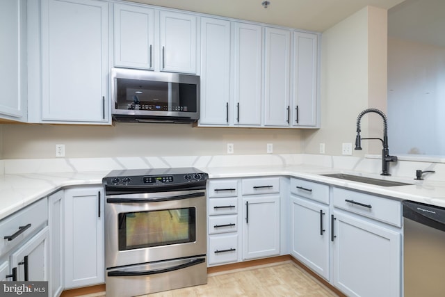 kitchen with light stone countertops, white cabinetry, appliances with stainless steel finishes, and sink