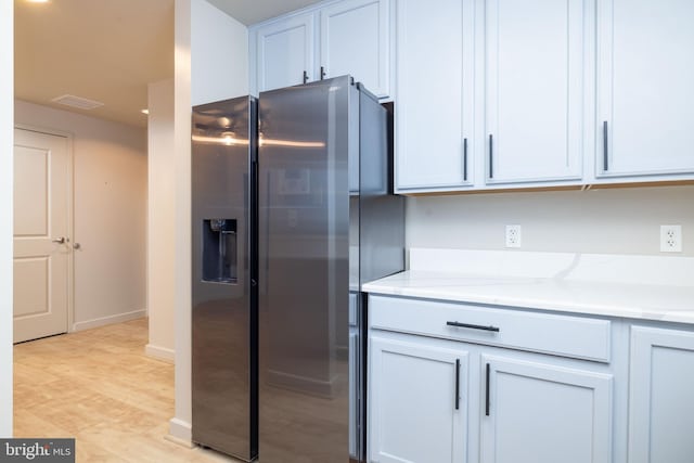 kitchen with white cabinetry, light stone countertops, stainless steel fridge with ice dispenser, and light hardwood / wood-style flooring