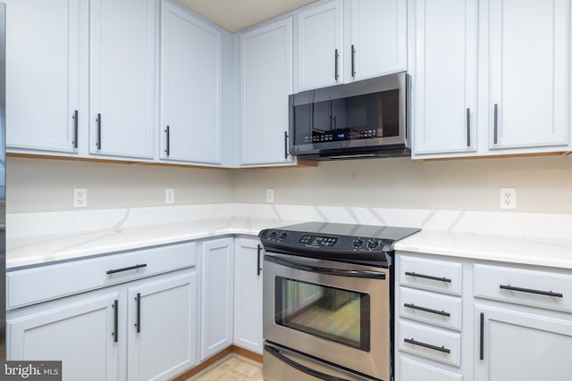 kitchen featuring light stone countertops, white cabinetry, and appliances with stainless steel finishes