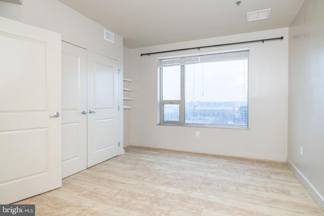 unfurnished bedroom with a closet and light wood-type flooring