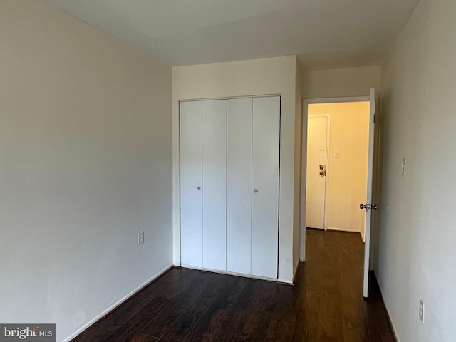 unfurnished bedroom featuring dark wood-type flooring and a closet