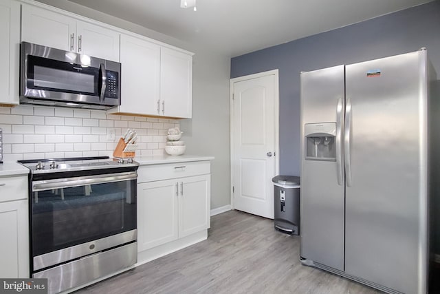 kitchen with appliances with stainless steel finishes, light hardwood / wood-style flooring, decorative backsplash, and white cabinets