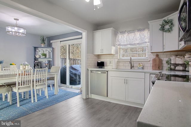 kitchen with appliances with stainless steel finishes, pendant lighting, white cabinetry, sink, and dark wood-type flooring