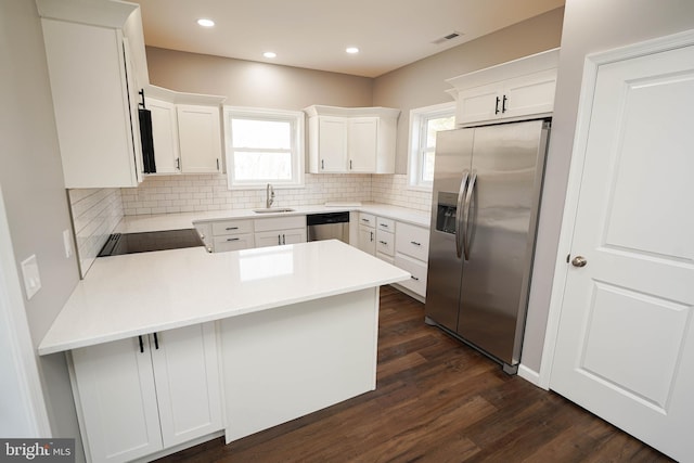 kitchen with white cabinetry, appliances with stainless steel finishes, kitchen peninsula, and decorative backsplash