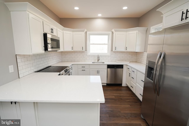 kitchen with stainless steel appliances, sink, white cabinets, and kitchen peninsula