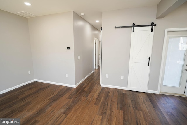 unfurnished room featuring dark hardwood / wood-style floors and a barn door