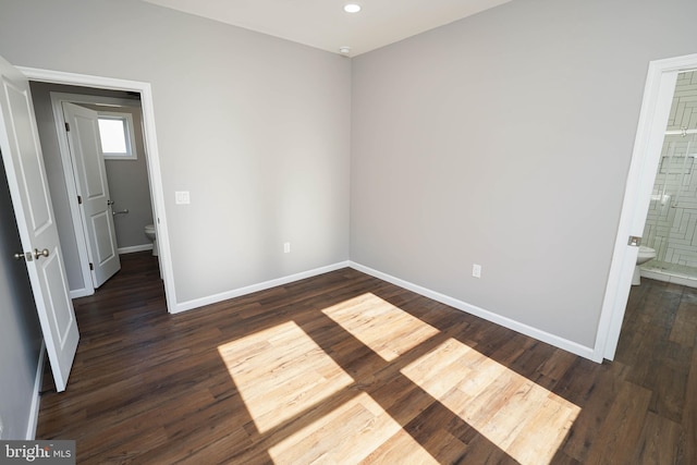 unfurnished bedroom with dark wood-type flooring and ensuite bath