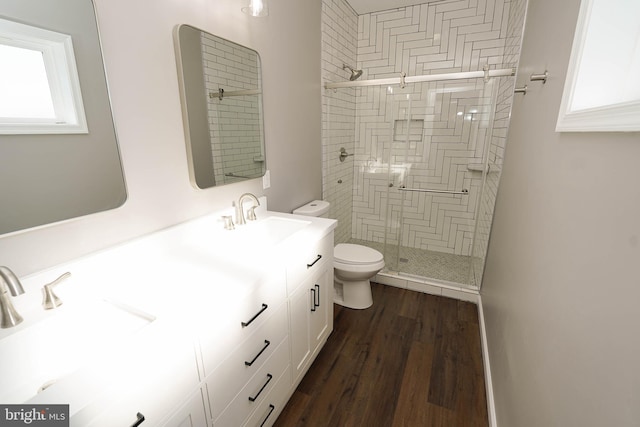 bathroom with hardwood / wood-style flooring, toilet, vanity, and a shower with shower door