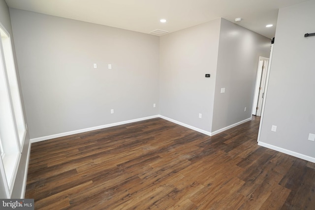 unfurnished room featuring dark wood-type flooring and a barn door