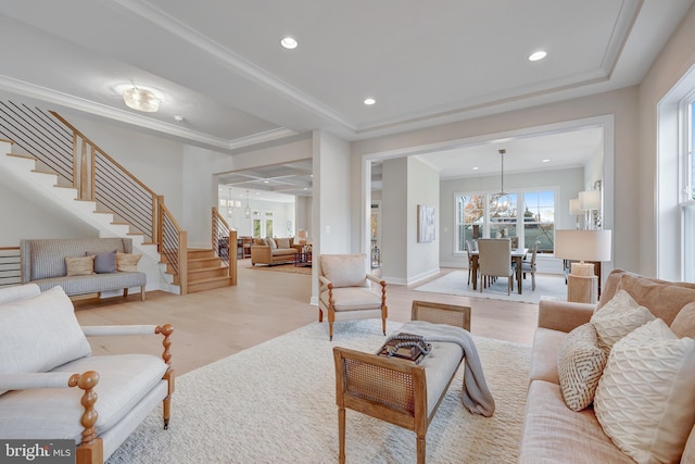 living room with a notable chandelier, crown molding, light hardwood / wood-style flooring, and a raised ceiling