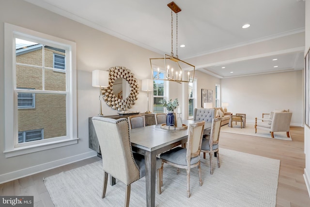 dining area featuring crown molding, an inviting chandelier, and light wood-type flooring