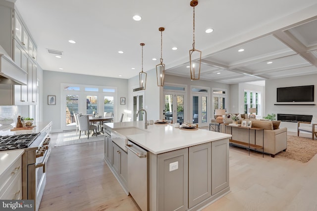 kitchen with french doors, sink, decorative light fixtures, stainless steel dishwasher, and a kitchen island with sink