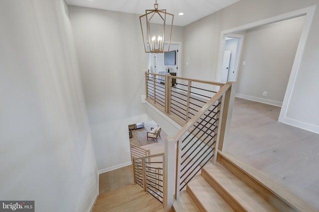 staircase with hardwood / wood-style floors and an inviting chandelier