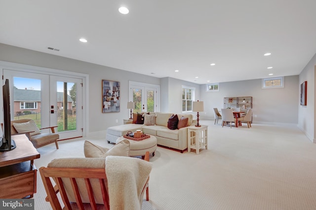 living room with a healthy amount of sunlight, light carpet, and french doors