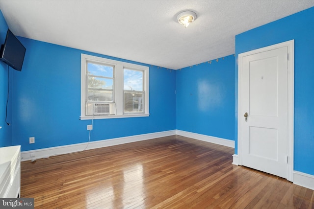 interior space featuring cooling unit, hardwood / wood-style floors, and a textured ceiling