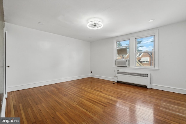 empty room with hardwood / wood-style floors and radiator heating unit