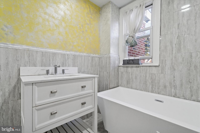 bathroom with vanity, a healthy amount of sunlight, tile walls, and a bathtub