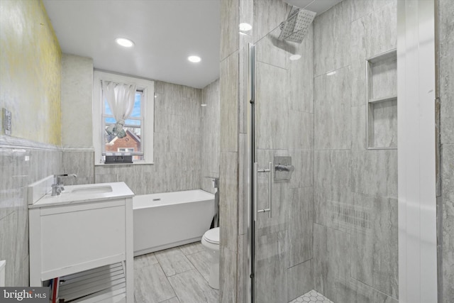 full bathroom with vanity, toilet, separate shower and tub, and tile walls