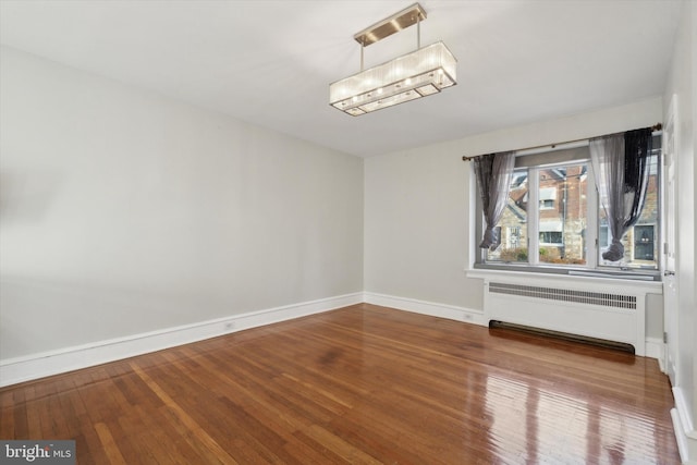 unfurnished dining area featuring radiator heating unit, a chandelier, and wood-type flooring