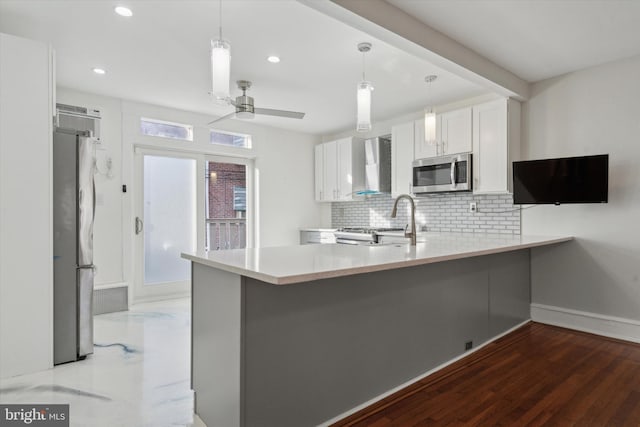 kitchen featuring sink, white cabinetry, stainless steel appliances, kitchen peninsula, and wall chimney exhaust hood