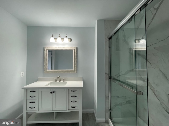 full bathroom with a marble finish shower, baseboards, and vanity