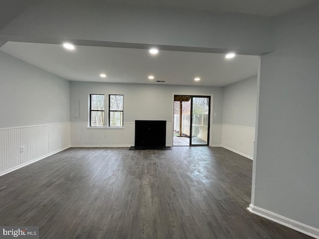 unfurnished living room featuring recessed lighting, dark wood-style flooring, and wainscoting