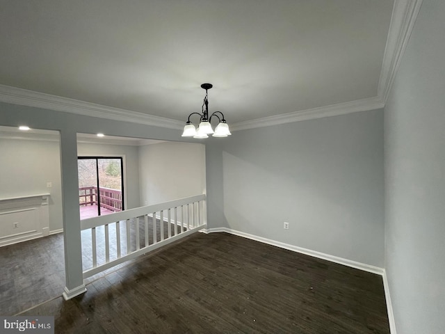 spare room with dark wood-style floors, ornamental molding, baseboards, and an inviting chandelier