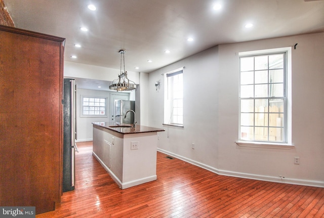 kitchen featuring dark wood-type flooring, sink, decorative light fixtures, a wealth of natural light, and a kitchen island with sink