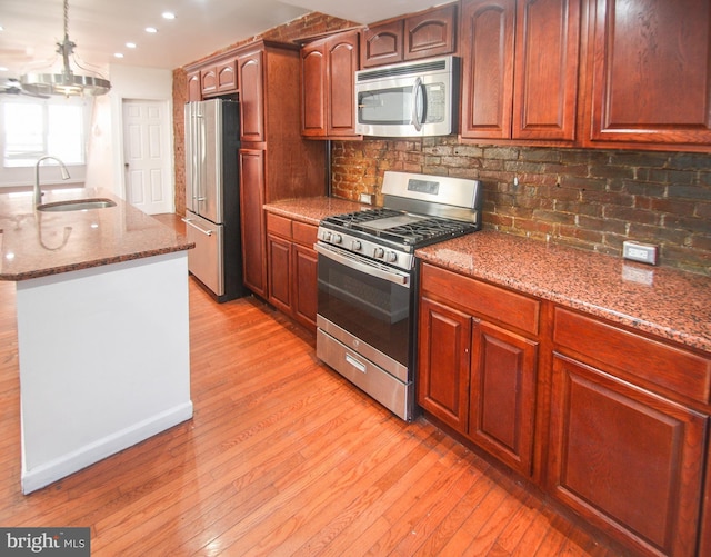 kitchen featuring stone counters, appliances with stainless steel finishes, tasteful backsplash, sink, and light hardwood / wood-style flooring