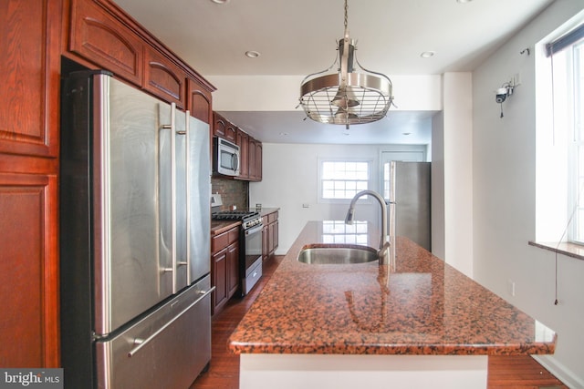 kitchen with stainless steel appliances, dark hardwood / wood-style flooring, sink, and dark stone countertops