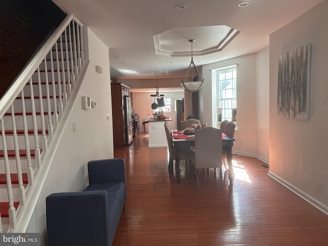 dining space featuring dark hardwood / wood-style flooring and a tray ceiling