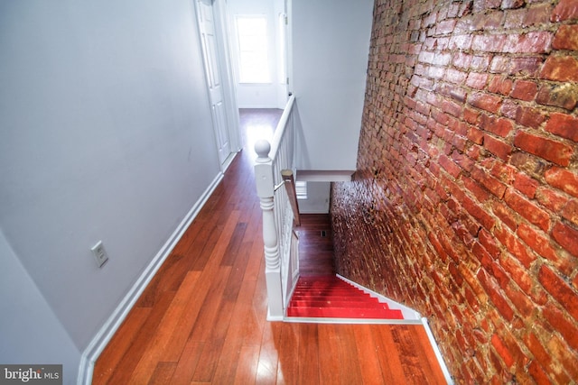 corridor with hardwood / wood-style flooring and brick wall