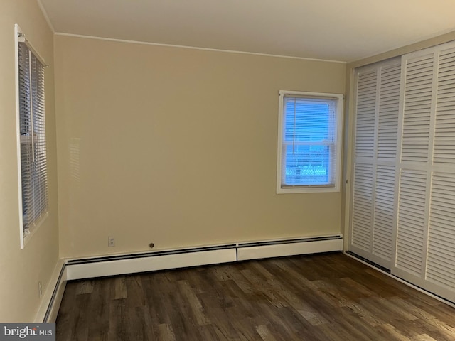 unfurnished bedroom with baseboard heating, dark hardwood / wood-style flooring, and a closet