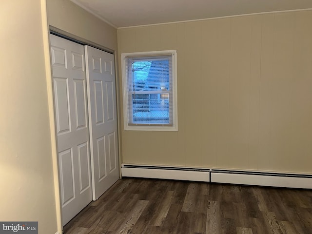 unfurnished bedroom with a baseboard heating unit, dark hardwood / wood-style floors, and a closet