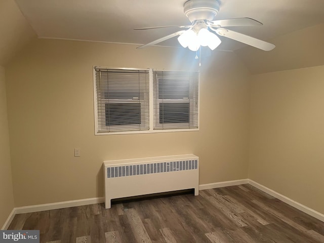 empty room with ceiling fan, lofted ceiling, radiator heating unit, and dark hardwood / wood-style flooring