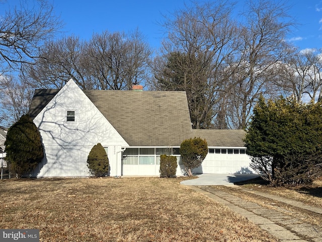 cape cod house with a garage and a front lawn