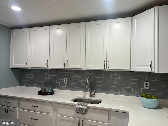 kitchen with backsplash, sink, and white cabinets