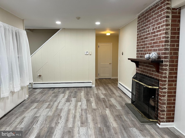 unfurnished living room featuring hardwood / wood-style flooring and a baseboard heating unit