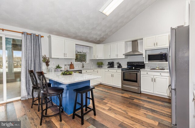 kitchen with stainless steel appliances, wall chimney range hood, white cabinets, and dark hardwood / wood-style flooring