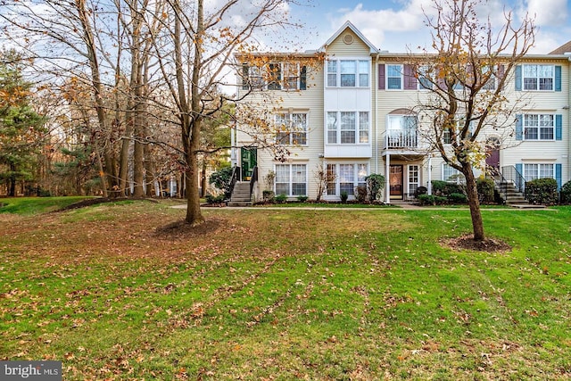 view of property with stairway and a front lawn