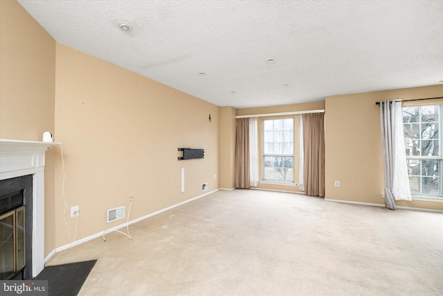 unfurnished living room with a fireplace with flush hearth, visible vents, baseboards, and light colored carpet