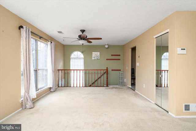 empty room with light carpet, a textured ceiling, and visible vents