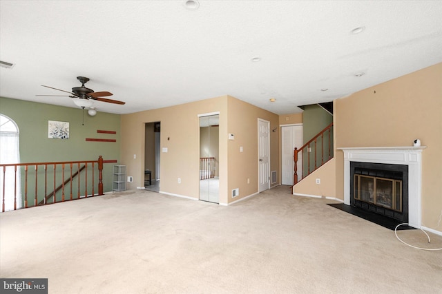 unfurnished living room with a fireplace with flush hearth, visible vents, baseboards, and light colored carpet