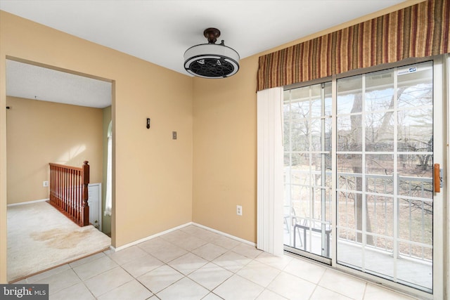 empty room with light tile patterned floors, light colored carpet, and baseboards