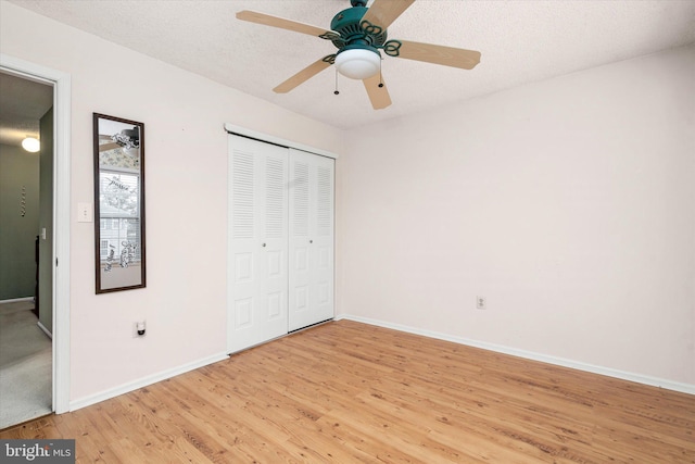 unfurnished bedroom with a closet, light wood-style flooring, a ceiling fan, a textured ceiling, and baseboards