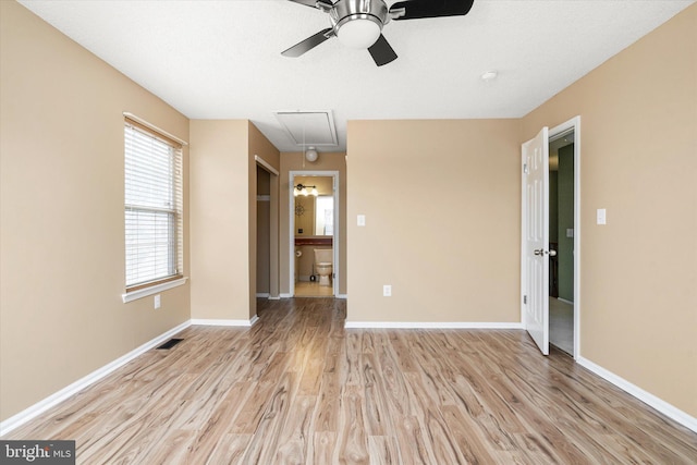 unfurnished room featuring attic access, visible vents, baseboards, and light wood-style flooring