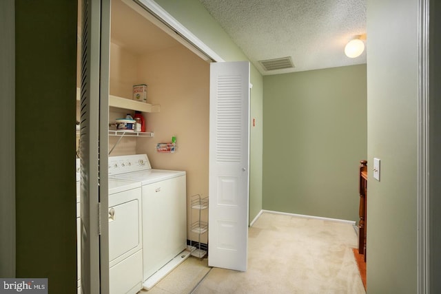 washroom with washing machine and clothes dryer, light colored carpet, visible vents, a textured ceiling, and laundry area