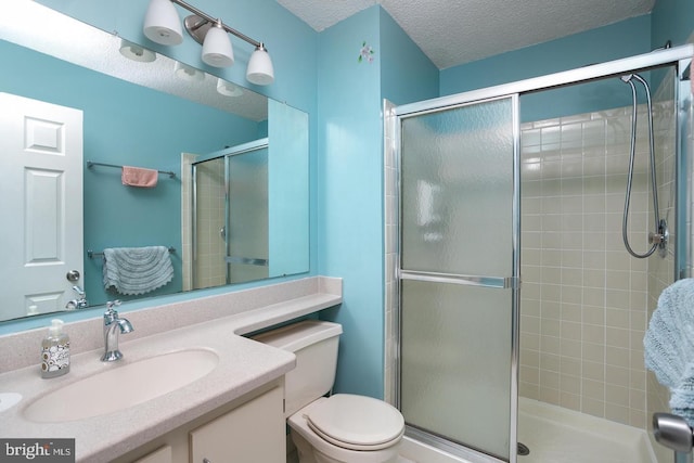 bathroom featuring toilet, tiled shower, a textured ceiling, and vanity