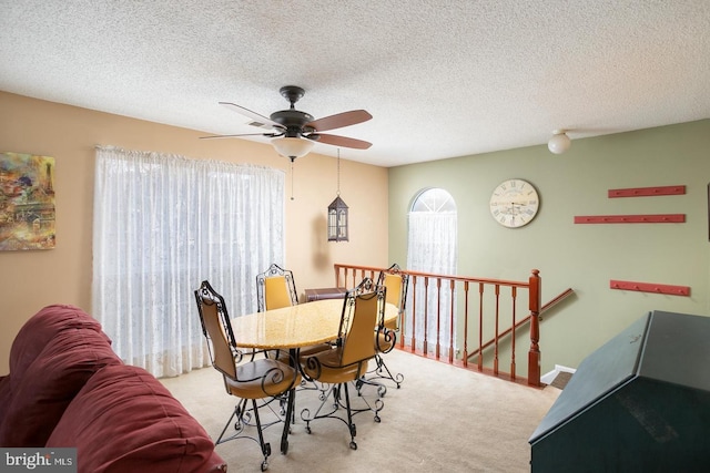 dining space with light carpet, ceiling fan, a textured ceiling, and baseboards