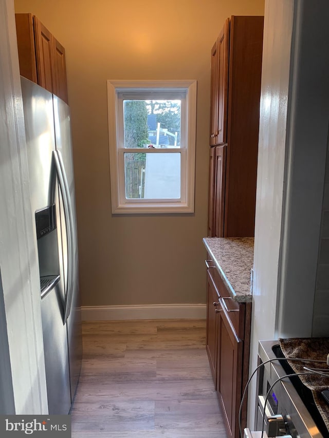 kitchen featuring light stone counters, light wood-type flooring, and stainless steel fridge with ice dispenser